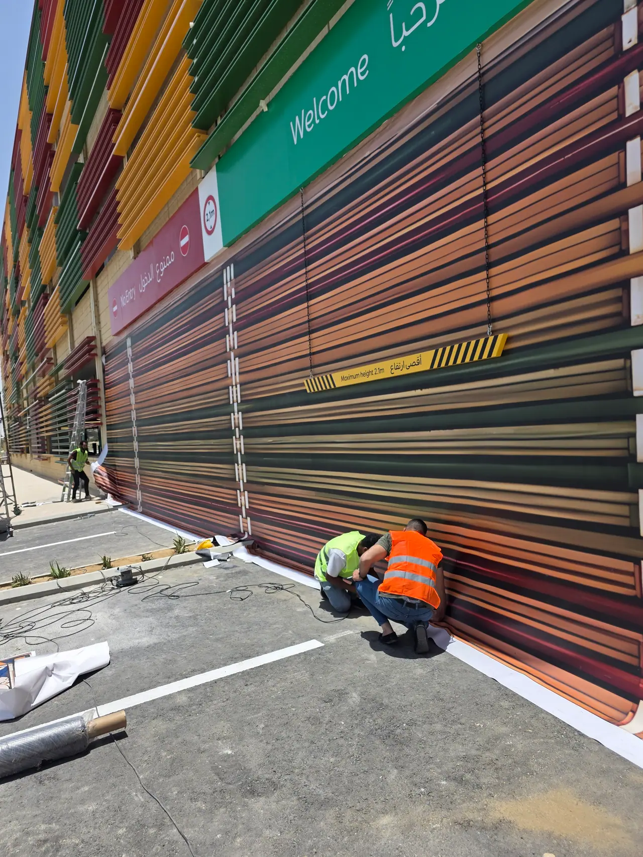 Seven Abha — Destination Graphics & Wayfinding — Our crew finishing the façade wrap at street level